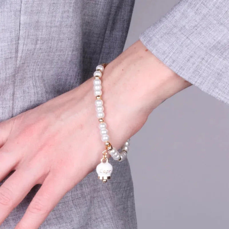 AMO CAPRI - BRACCIALE METALLO DORATO CON SFERE E CAMPANELLA BIANCA
